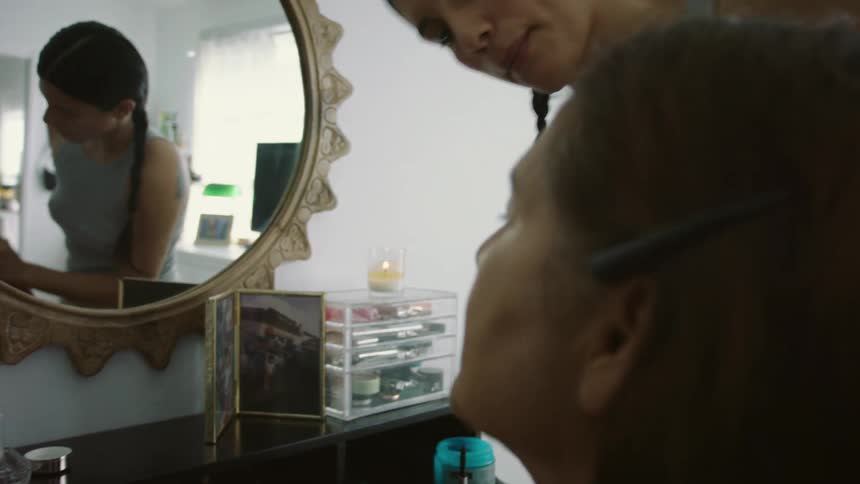 A woman is applying makeup on someone else in a room