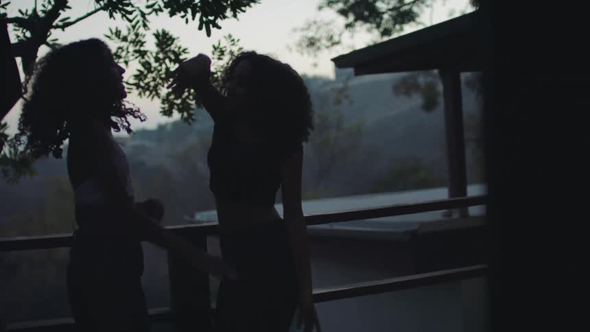 Group of young girls dancing and jumping excitedly on the balcony of a house at morning