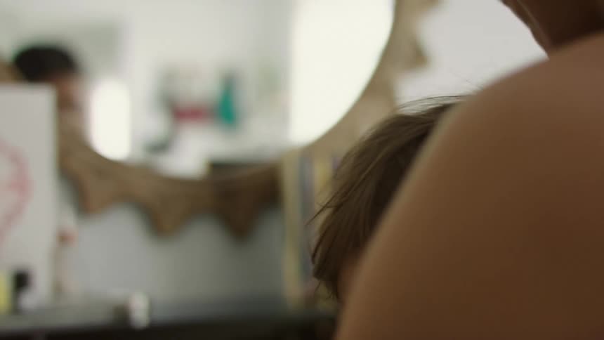 Toddler breastfeeding while mother is applying makeup