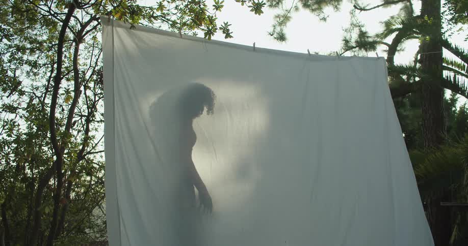 A woman is standing behind a blanket outdoors in spring