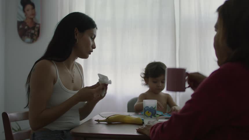 A women sits at the table talking and laughing with her mother while her daughter plays