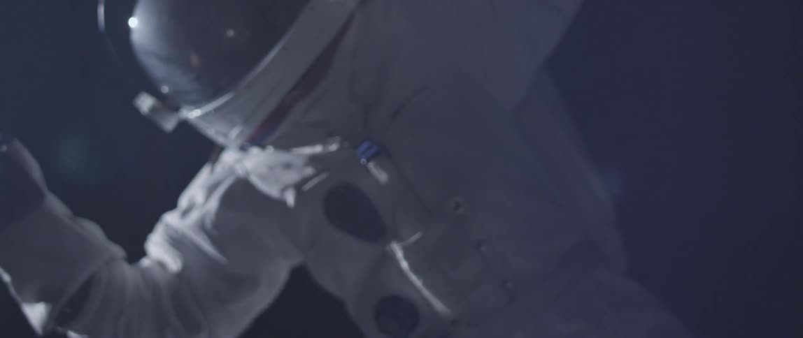 An astronaut is floating in a dark area