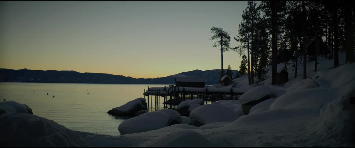 A view of a lake at sunrise in a snowy area