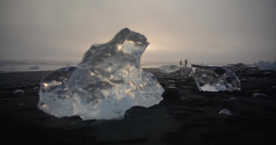 A piece of ice is on the beach coast at dusk