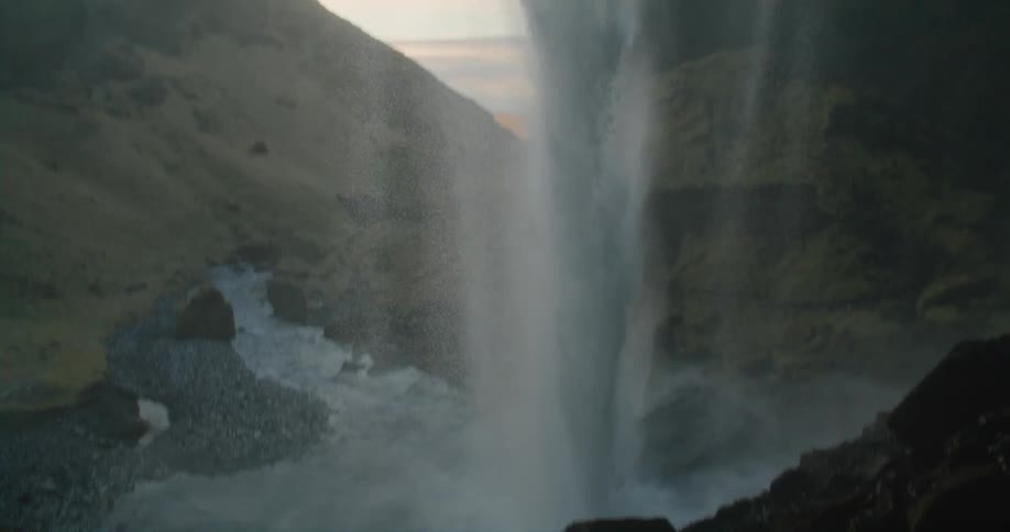 Water flows in a rush past a cave entrance splashing into the river basin