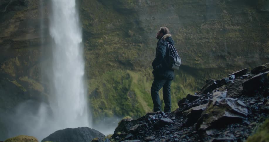 A man watches a waterfall crashing in to a river