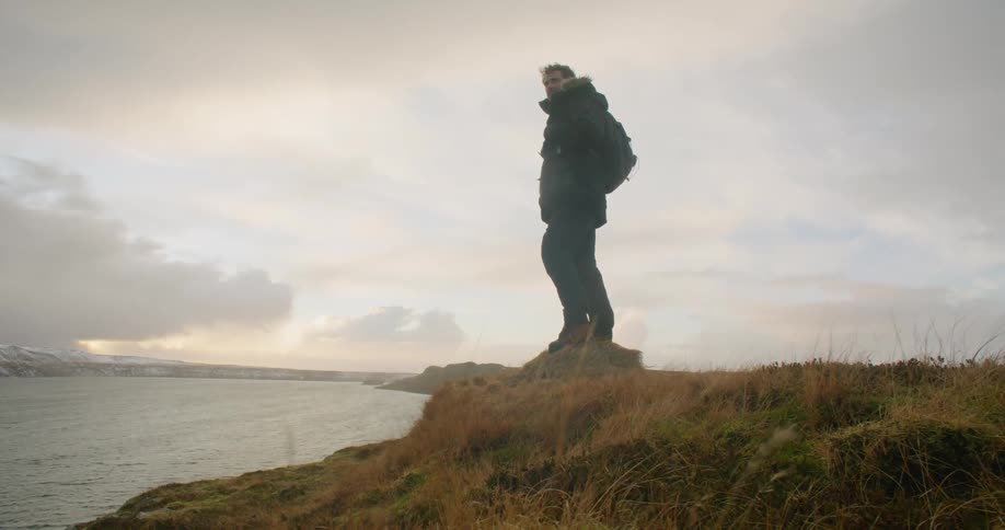A man is standing on the coast and looking into the horizon