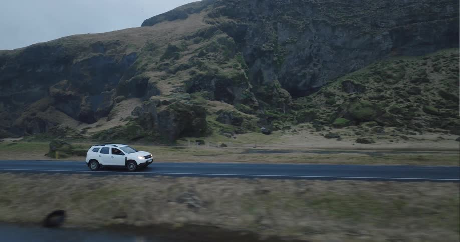 A white suv traveling on a rural road on a rainy day
