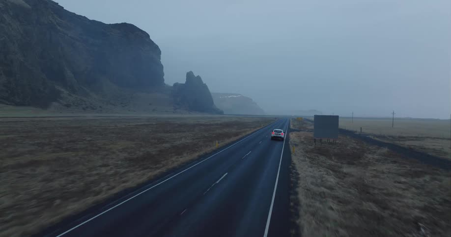 A car is driving down the highway on a foggy day