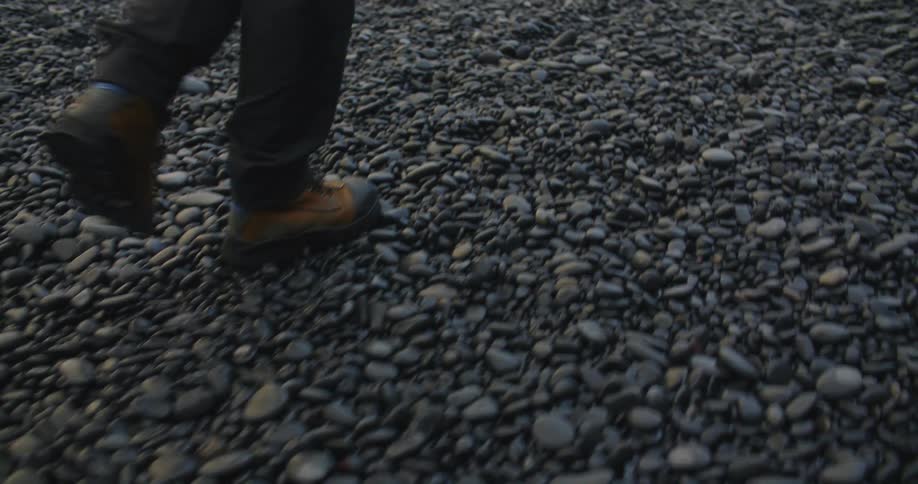 Young man walking on the reynisfjara black sand beach at sunset