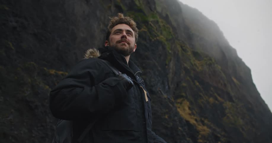 A man is looking around by the mountain