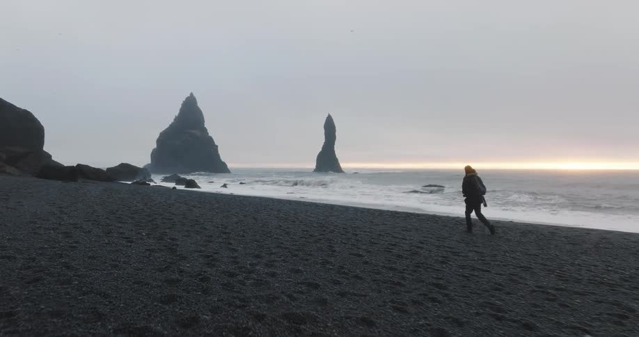A man walks along the beach as waves roll in