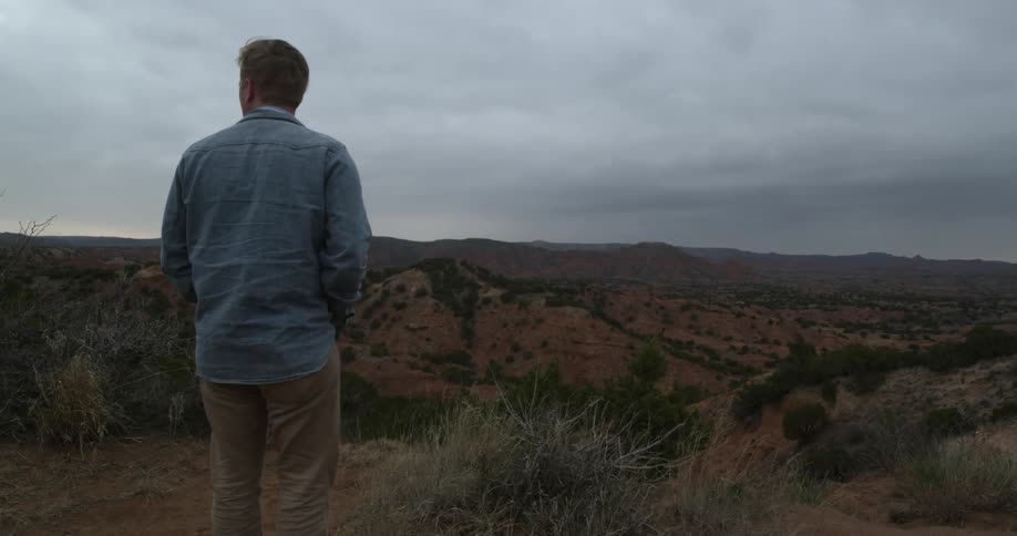 A man walking through the desert on a cloudy night