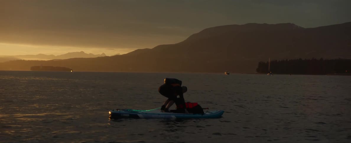 A person is on the lake in a kayak at sunset