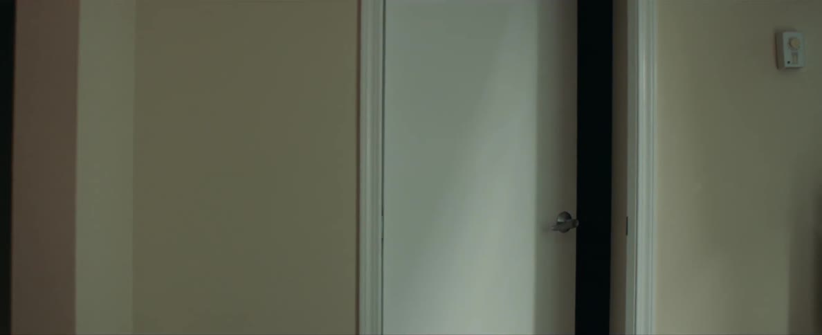 A woman is standing in a room and the door is ajar
