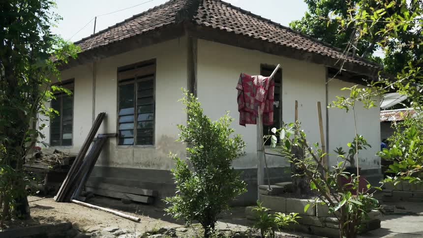 A small home has many trees and bushes around it