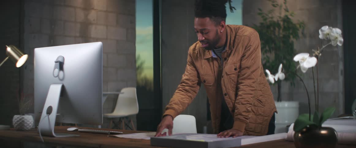 A man looking over a document on a computer desk in an office setting