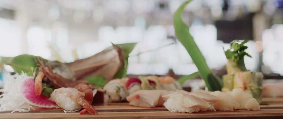 Plate of sushi served over a wooden board on a restaurant
