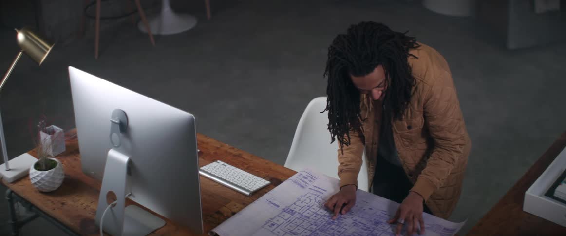 A man looks over blueprints while standing at his desk
