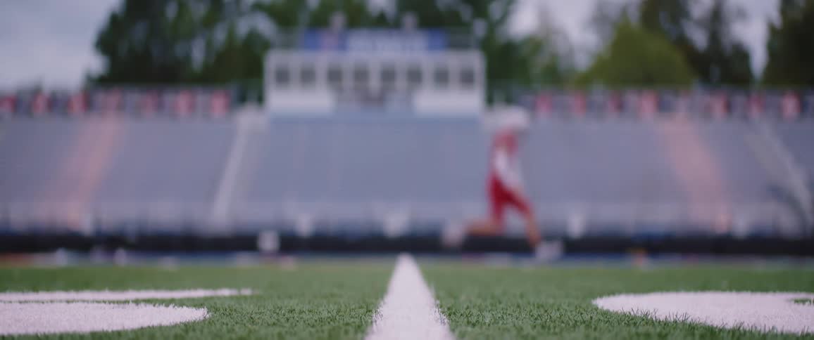 Out of focus football player wearing a red uniform practicing on a football field