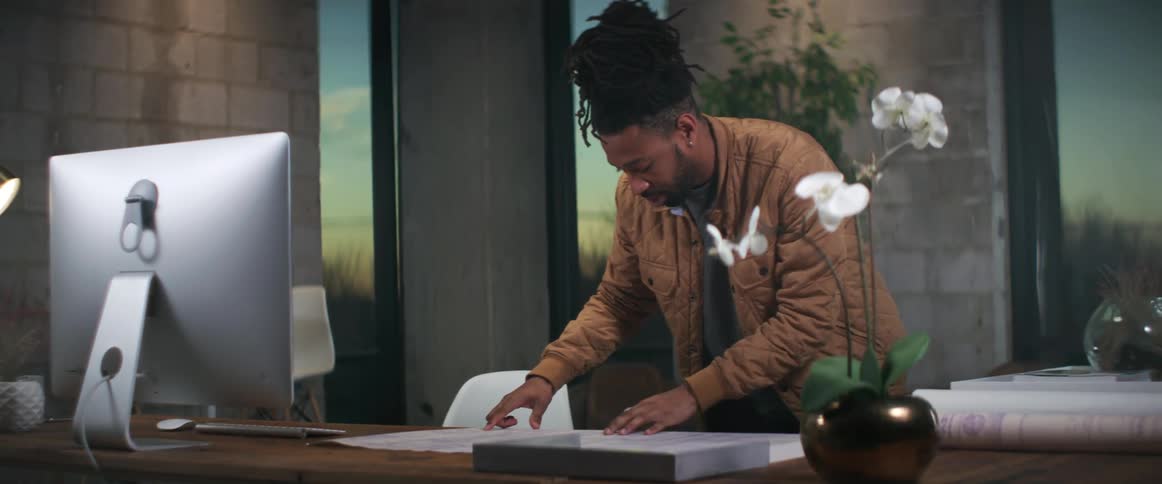 A man looks at blueprints while standing at his desk