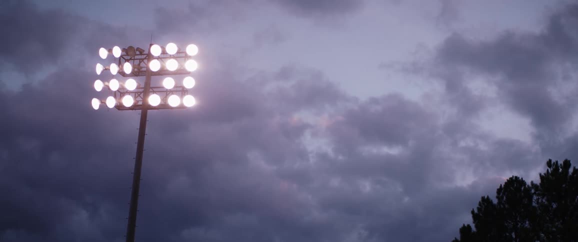 Floodlights at a football stadium high in a cloudy sky