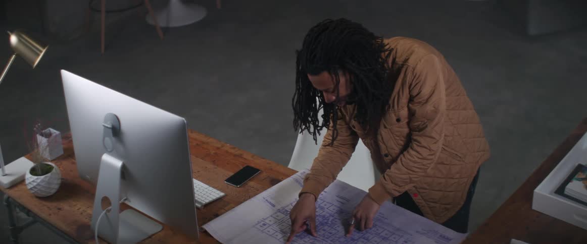 A man is standing at a desk looking at a map