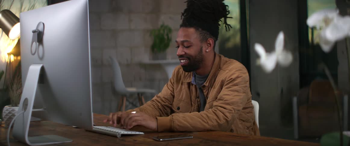 A man is smiling as he uses his computer