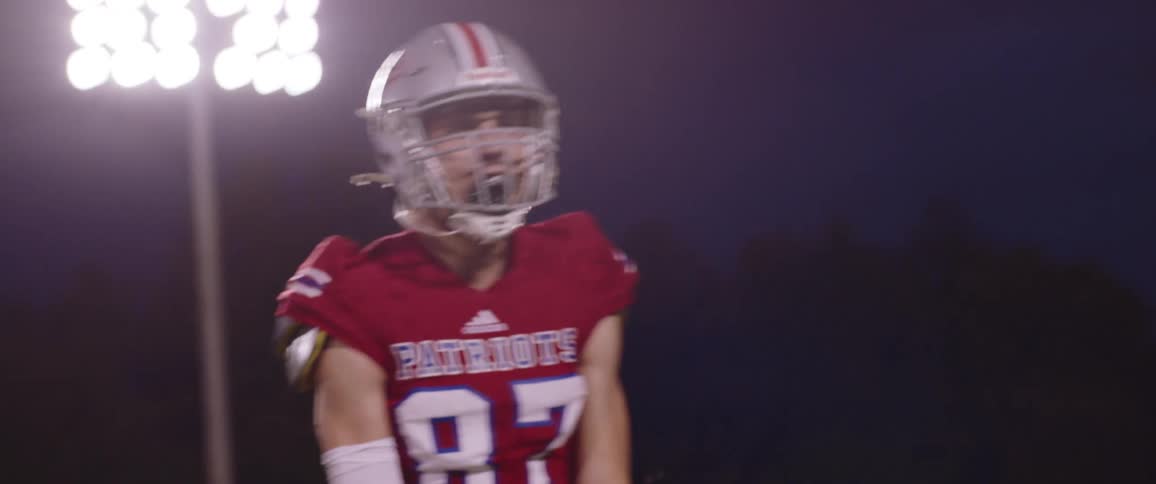 Football player wearing red uniform celebrating in the stadium at night