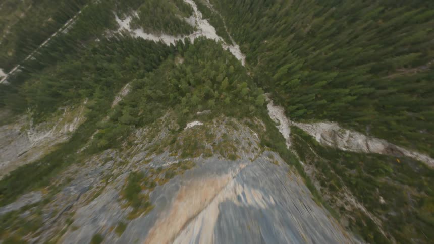 Conifer trees cover mountain side leading down to ice covered river
