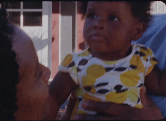 A father and mother smiling and interacting with their baby outside