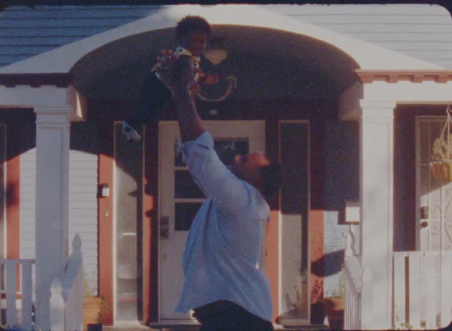 A father is holding his son outside of his house