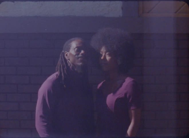 A man and woman stand outside a house and pose for a photo