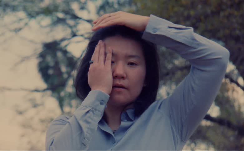 A woman touches her face with both hands during a modern dance performance