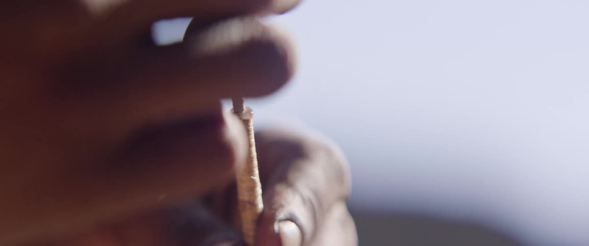 Close up of tribal mans hands making arrow for hunting
