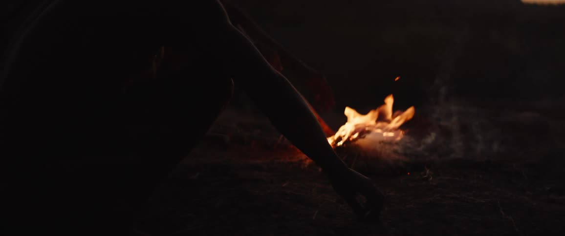 Father and son build a fire outside at night