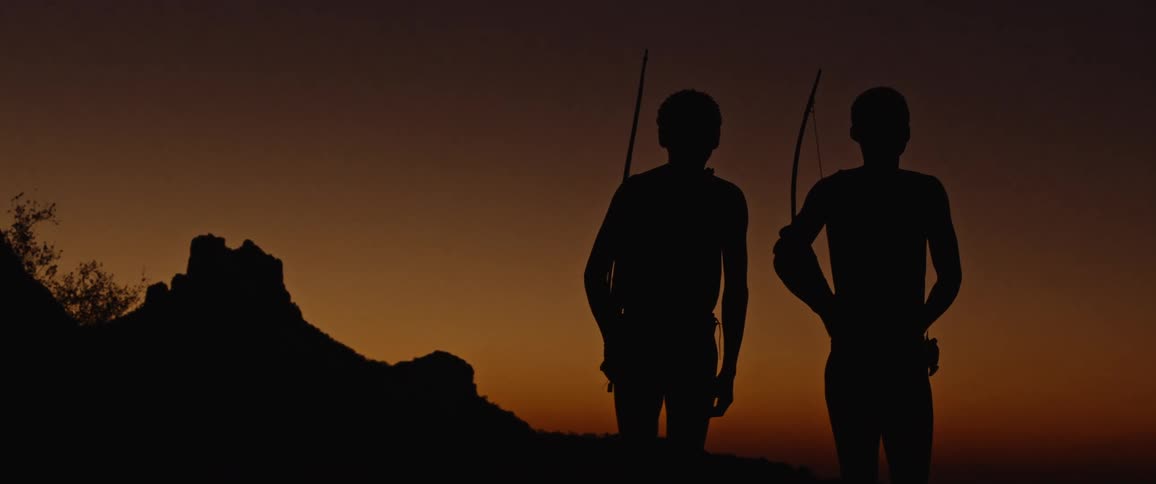 Silhouettes of tribal men with bows over their shoulders