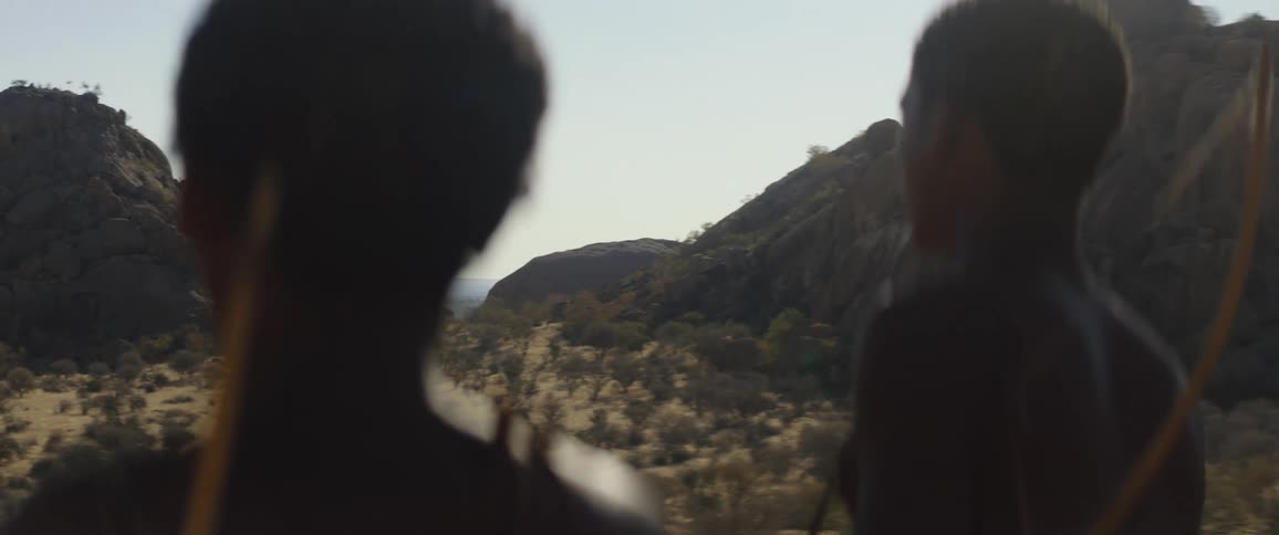 Father and son stand with bows and look across the land