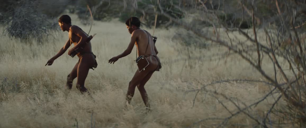 Two tribal men tracking prey in field