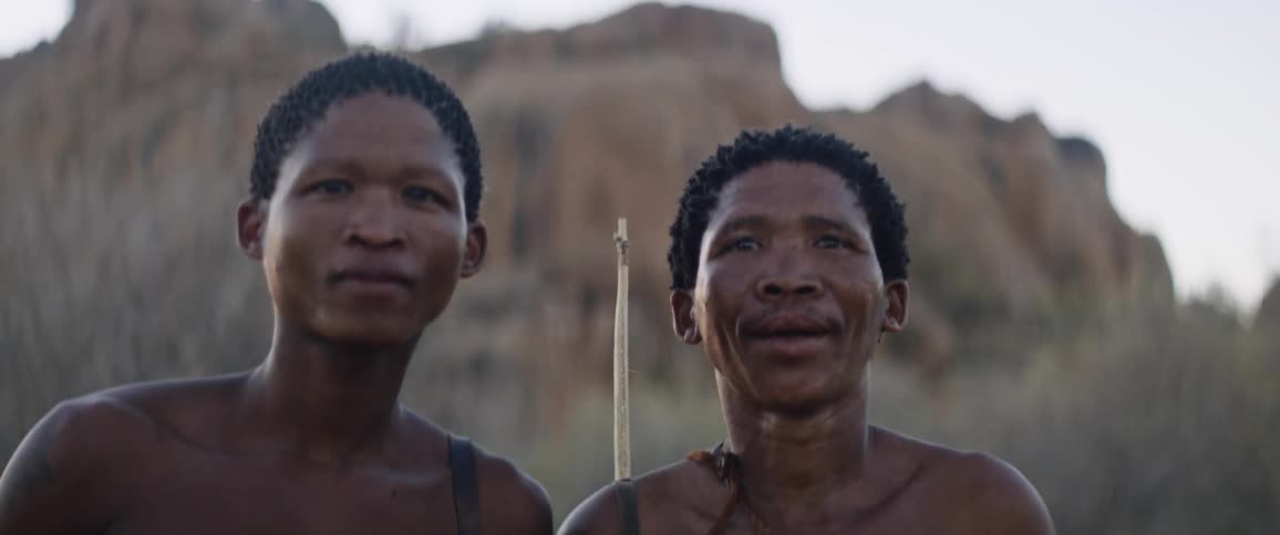 Tribal men stand in front of a rock formation in africa