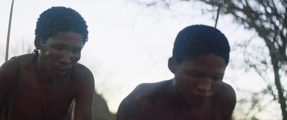 Two hunters walk low to the ground as they hunt with bows and arrows