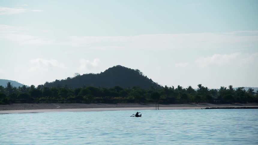 A person paddles a boat near the shore