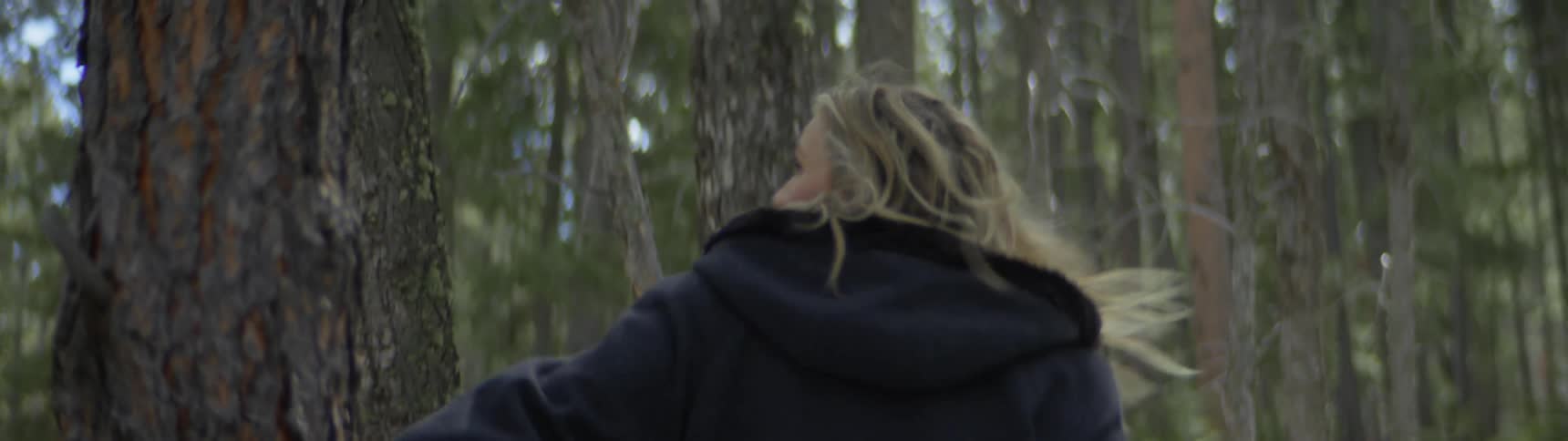 A frightened woman turns looking back and around in the forest