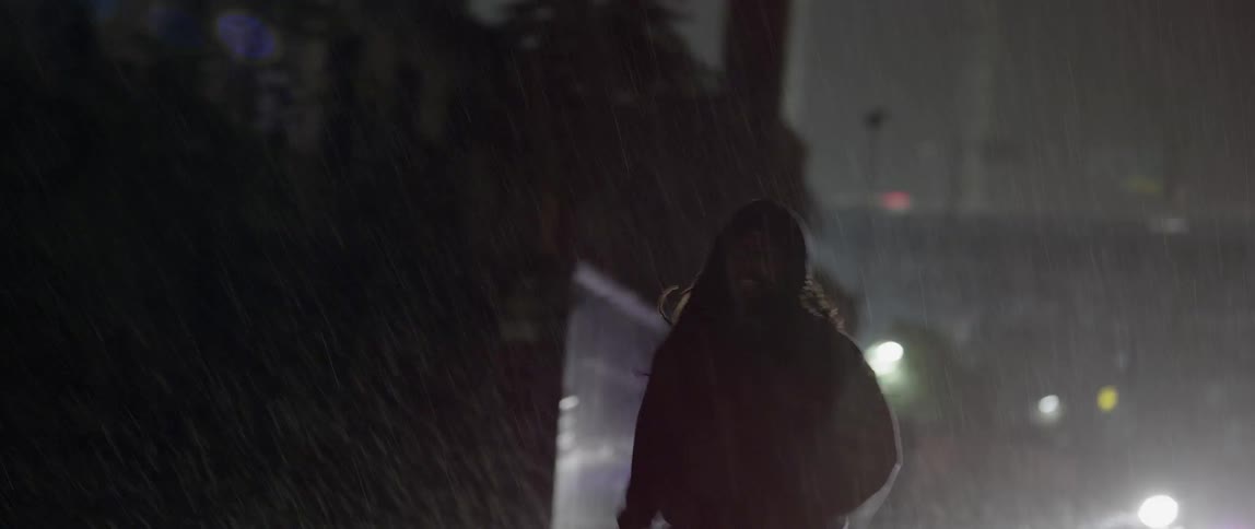 A person runs down the street in the rain
