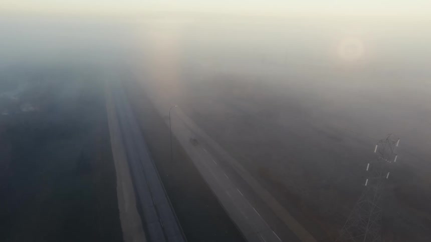 Cars are driving on a road in a rural area