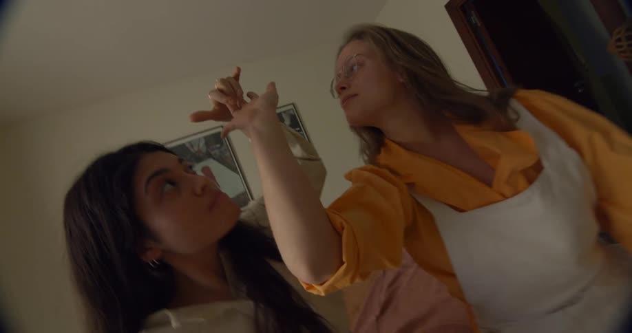 Two women sway in bedroom holding hands