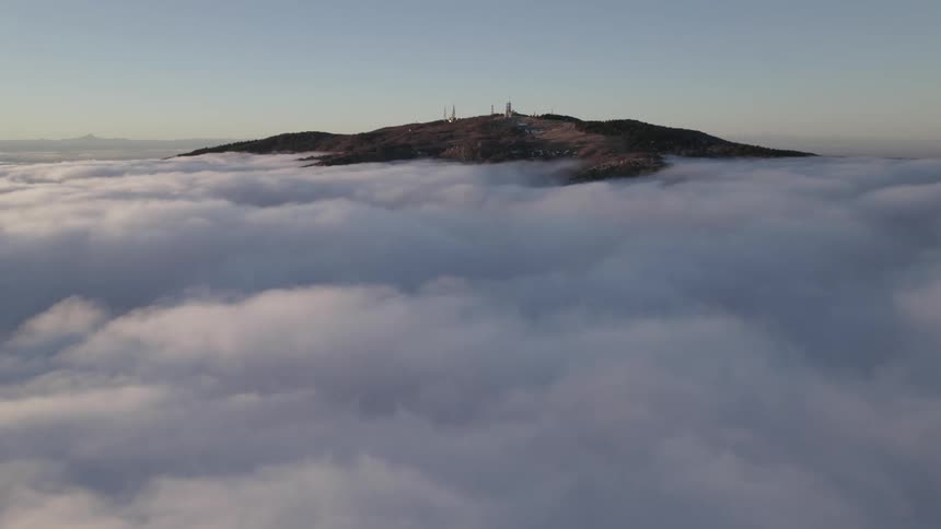 Aerial view of mountain with buildings above the clouds