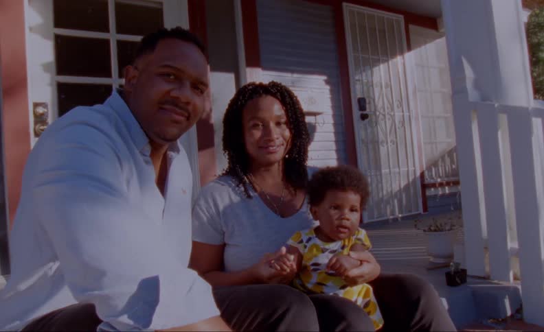 Family sits on front porch steps smiling as they pose