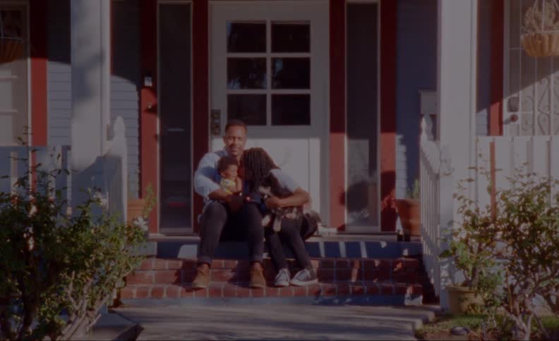 As family sits on porch steps mother leans over to kiss child sitting in fathers lap