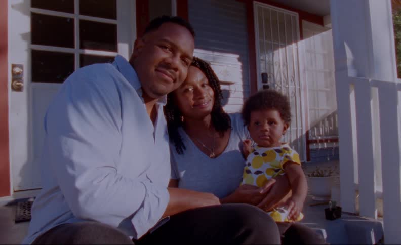 Parents smile while sitting on porch steps with child
